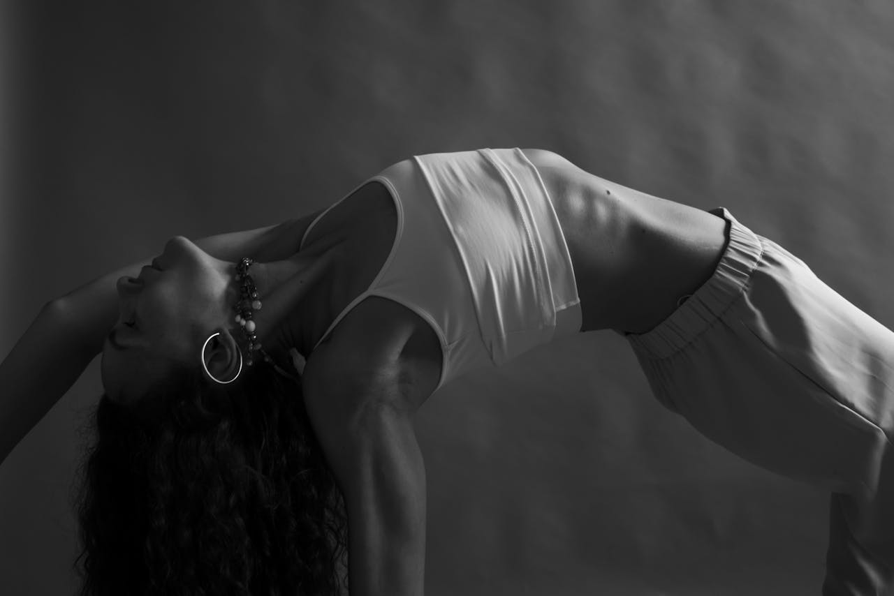 Monochrome image of a woman practicing yoga in a studio setting, emphasizing mindfulness and wellness.
