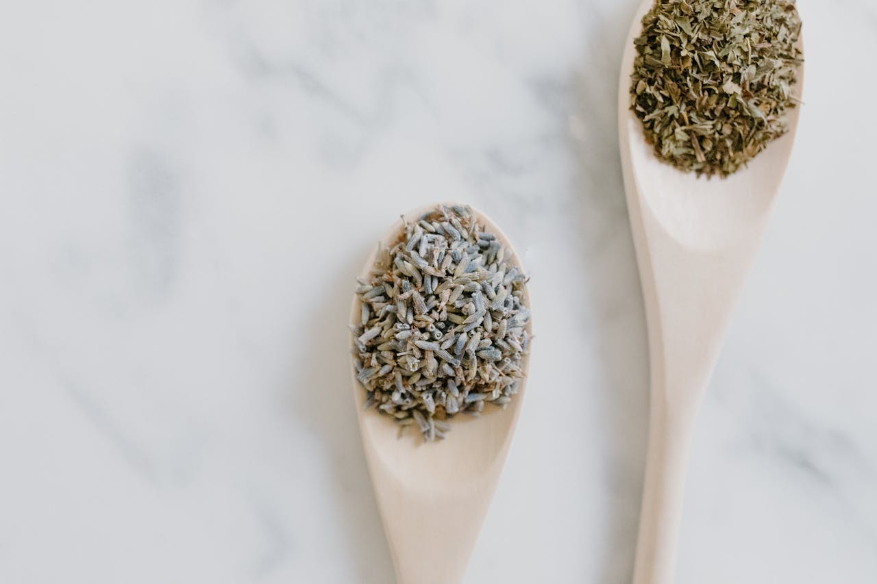 Aesthetic close-up of dried lavender and herbs on spoons, perfect for aromatherapy and cooking.